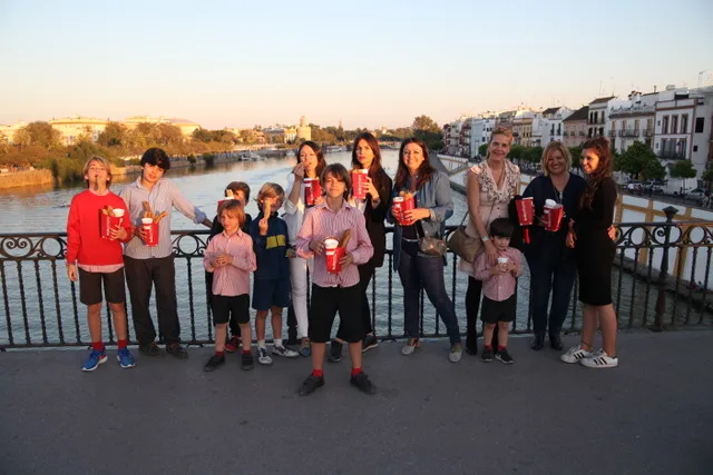 Group holding Kukuchurro churros on Triana Bridge, with Calle Betis behind