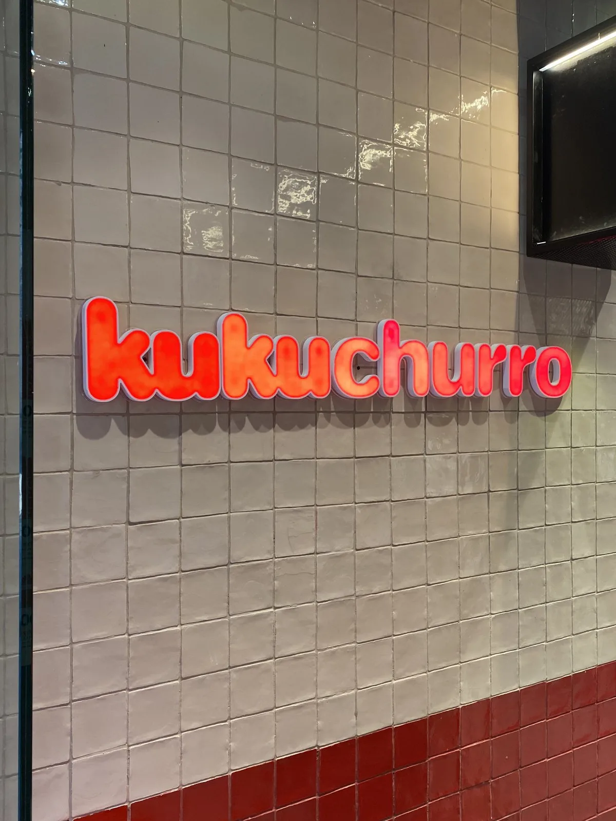 Inside Kukuchurro Catedral, white tiled wall with the red logo